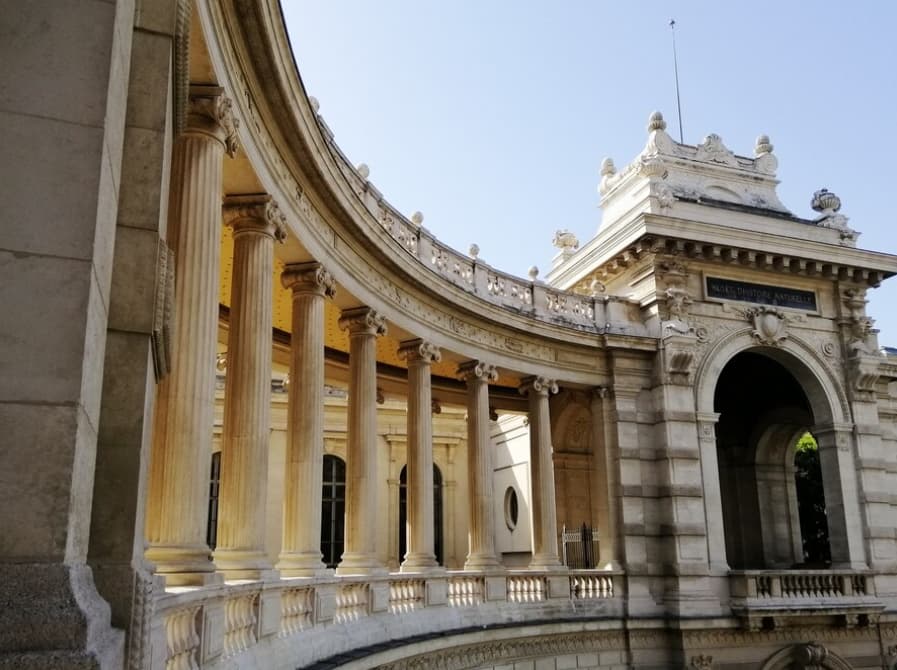 Sunlit columns line the curved arcade of the Palais Longchamp